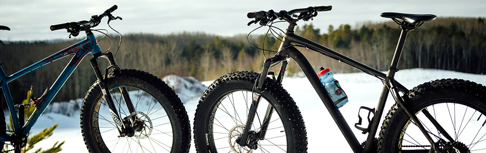 two fat bikes parked on a snowy hill