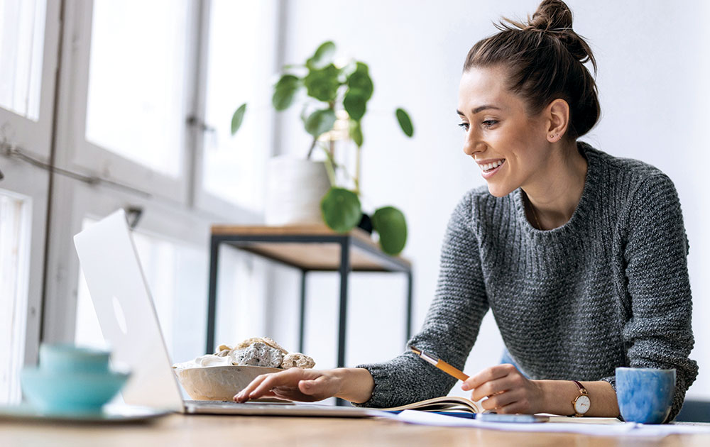 woman working on laptop from home smiling