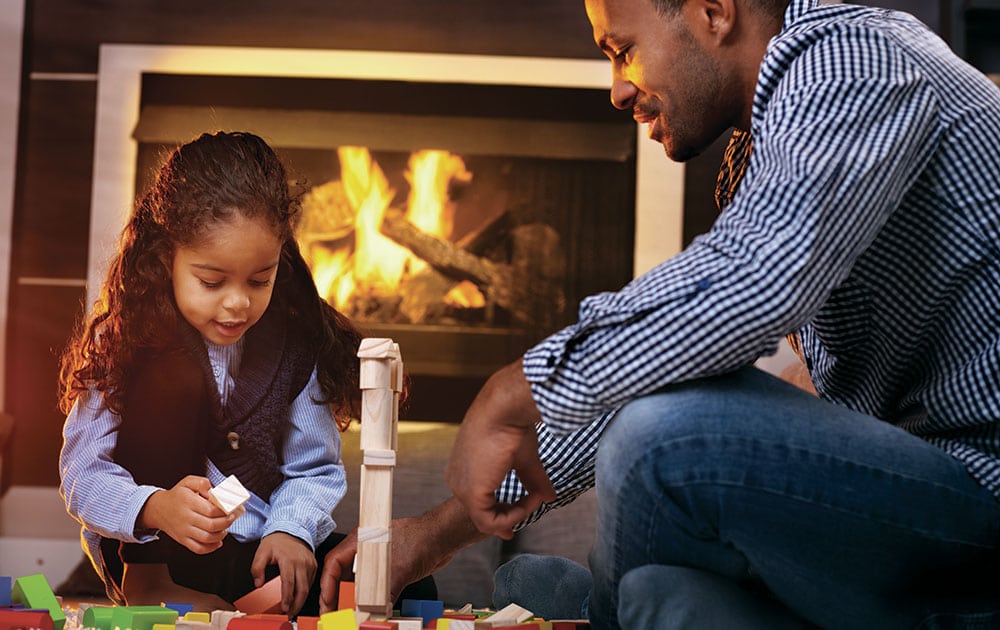 dad and daughter play blocks near fireplace