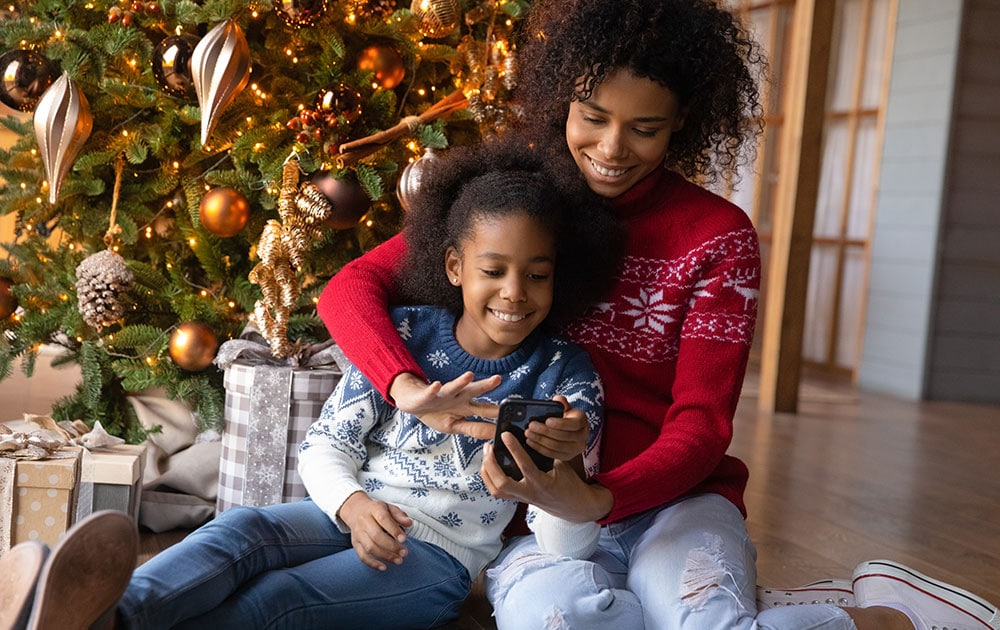 mother daughter by christmas tree cell phone