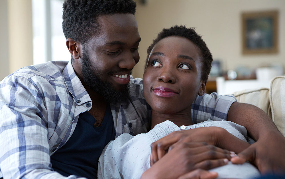 pregnant couple cuddle couch